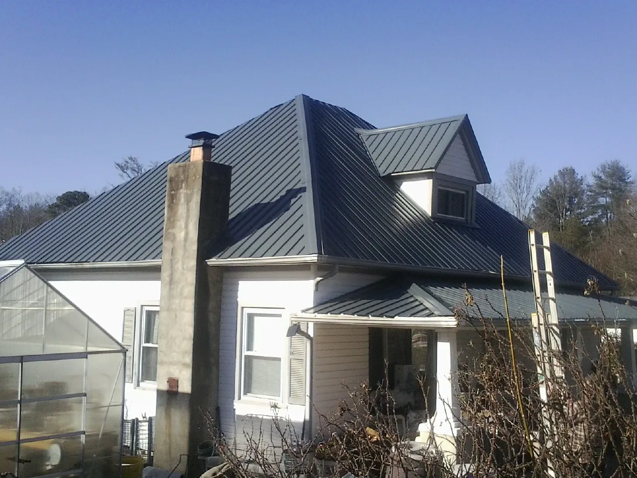 Dark blue standing seam metal roof on a white farmhouse with dormer — Slate & Tile Roof Repair by Roofing Brothers in Accident