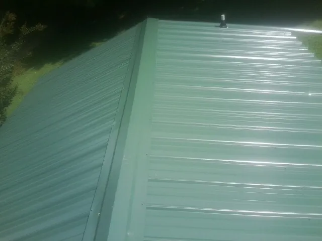 New green metal panels meeting at the ridge of a roof — Flat Roof Repair work by our crew in Accident