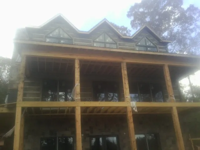 Dormers and porch framing on a large log home under construction — Roof Coating work by our crew in Accident