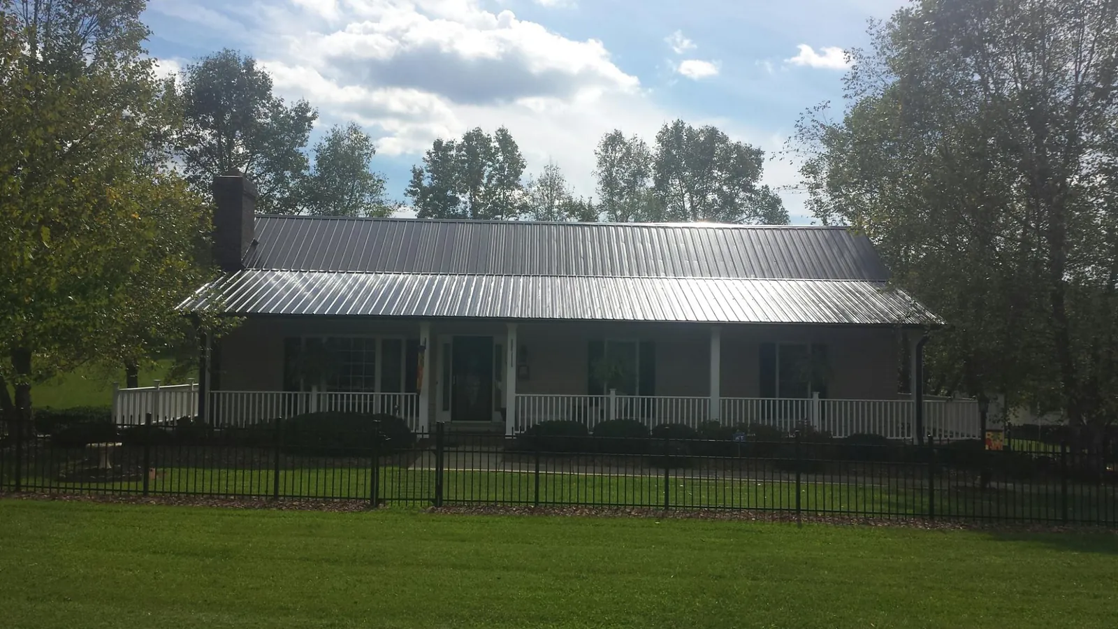 Gray metal roof on a brick ranch with a full width front porch — Gutter Guard Installation work by our crew in Accident