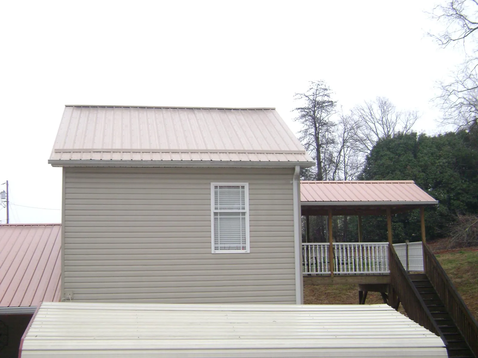 Tan metal roofs on a two story addition and attached porch, from a Roof Replacement job in Accident